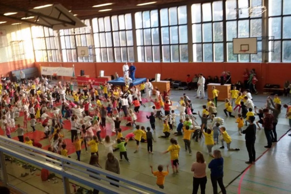 Momentaufnahme vom Tag des Judo. Eine Sporthalle ist gefuellt mit Teilnehmenden und Eltern.