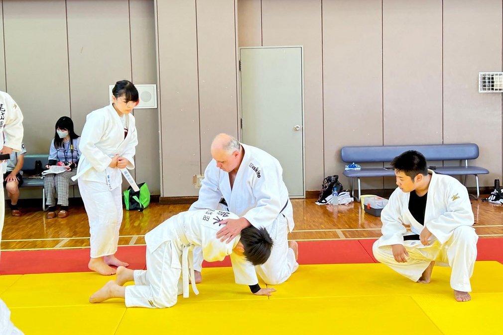 Ein Trainer zeigt einer jungen Judoka eine Uebung auf der Judomatte.