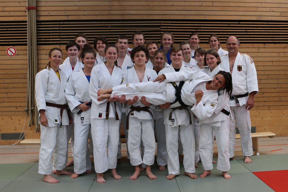 Eine Gruppen junger Judoka posiert fuer ein Gruppenfoto.